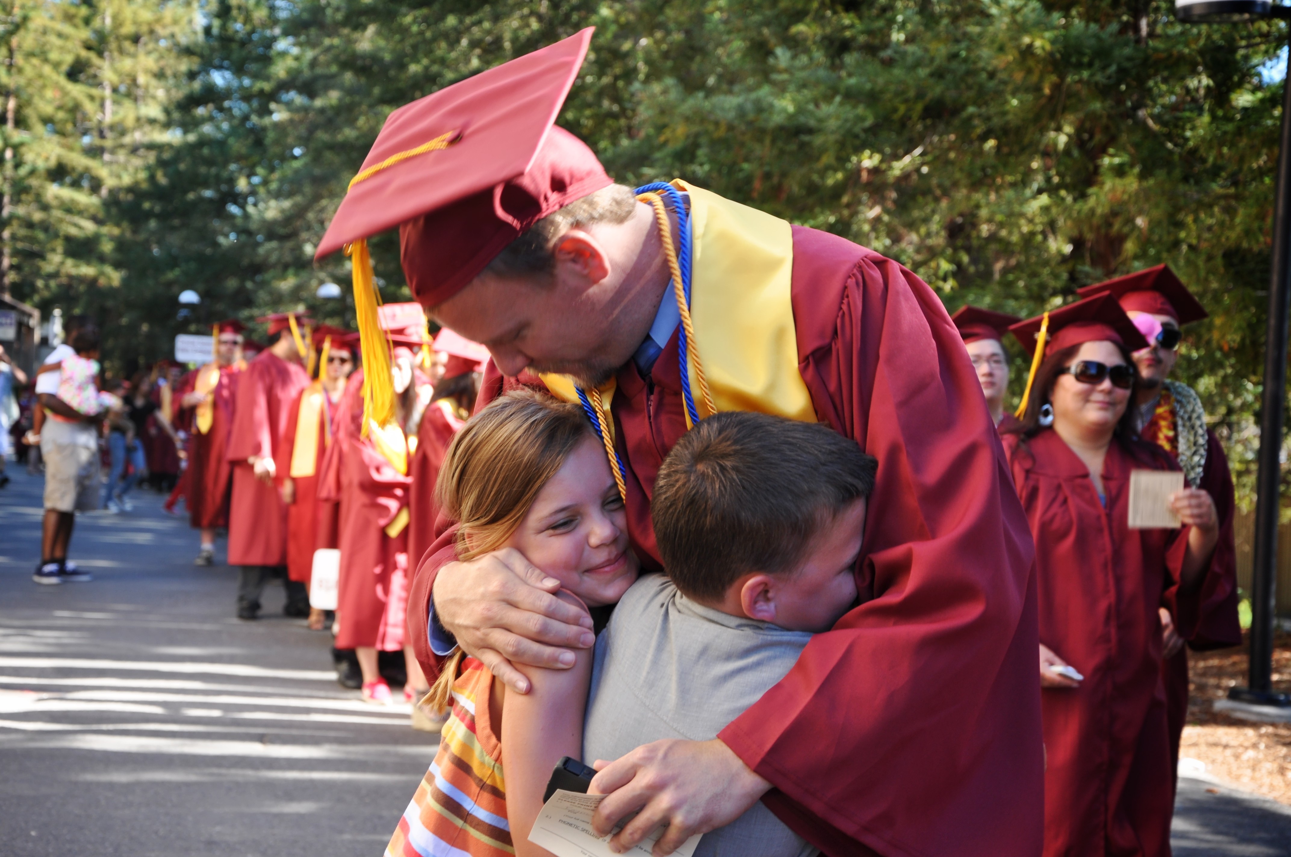 Graduate hugging kids